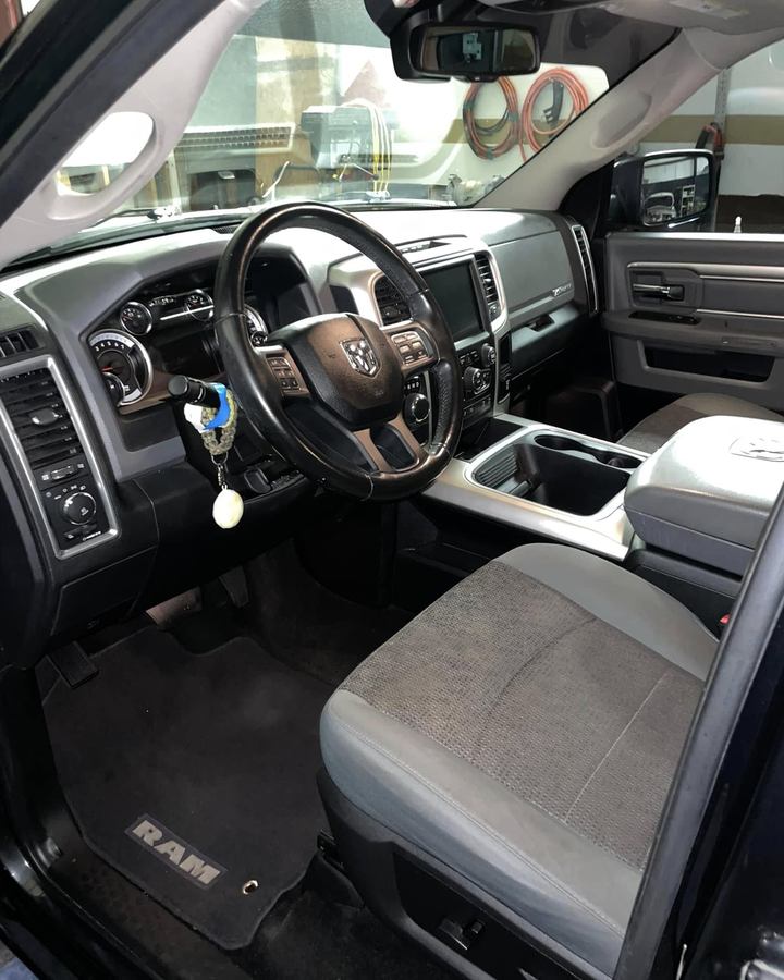 Grey cloth front seats and dash of a Ram after an interior detail, mats and console clean