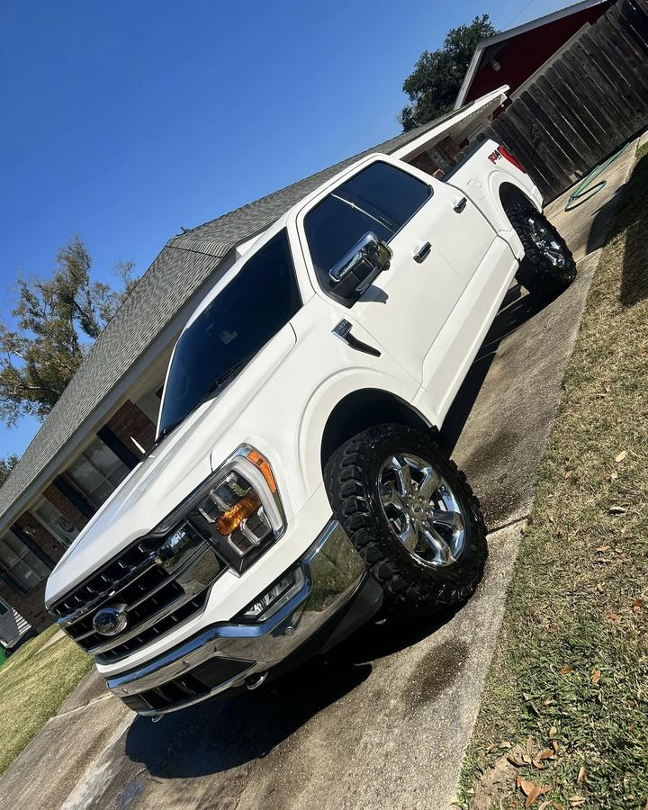 White lifted Ford F-150 on a driveway after a detail, chrome grille and wheels shining