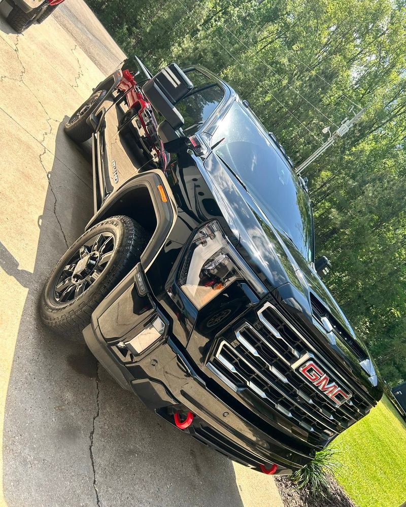 Black GMC Sierra front end in a driveway after a detail, deep gloss paint