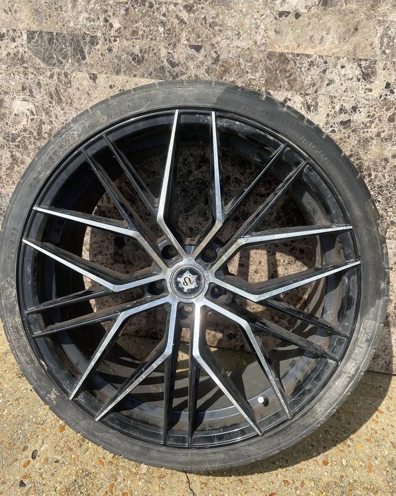 Black and machined aftermarket wheel leaning against a wall after a polish